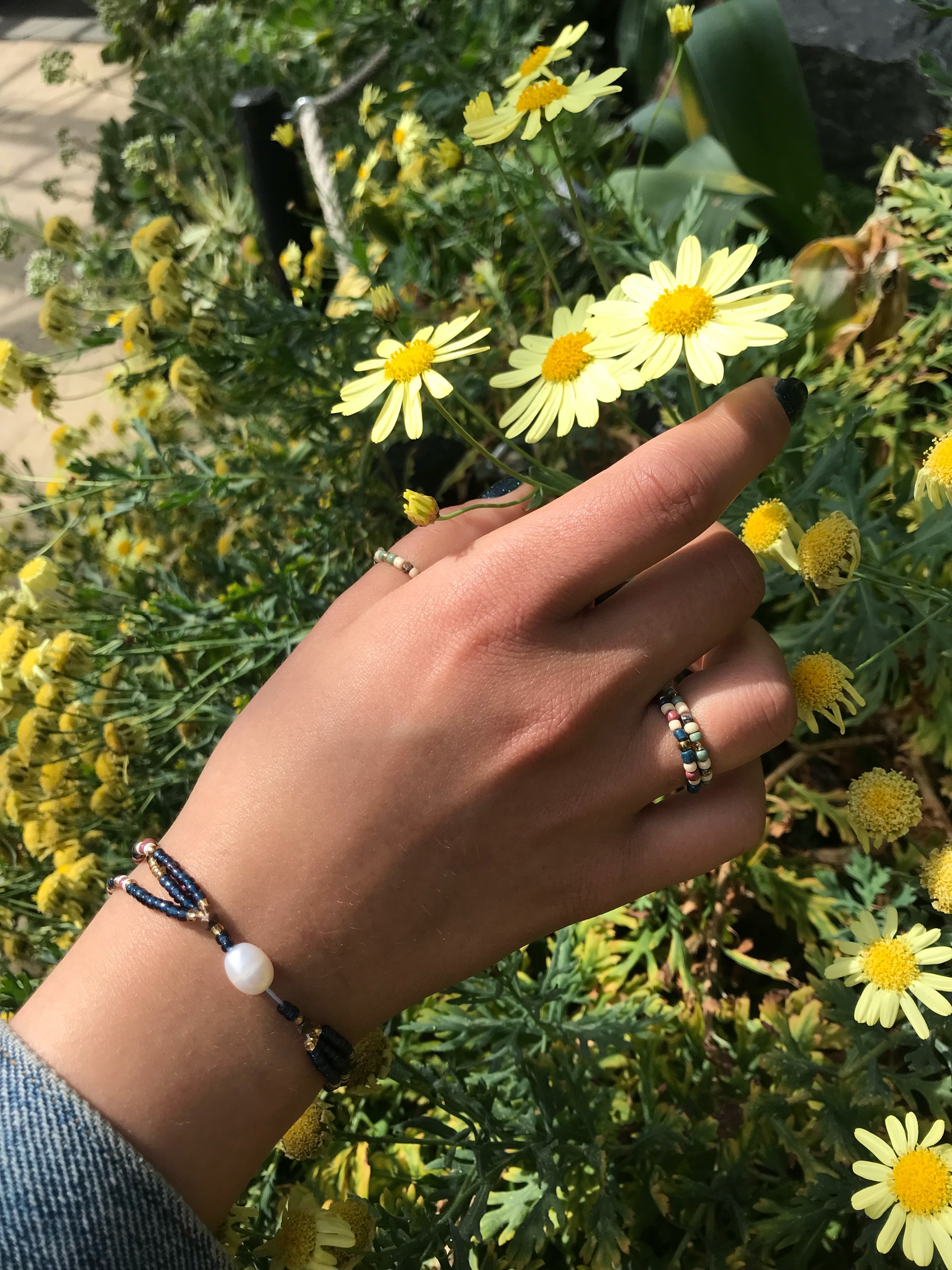 up-cycled, indigo,
            beaded, pearl bracelet and beaded rings on floral background