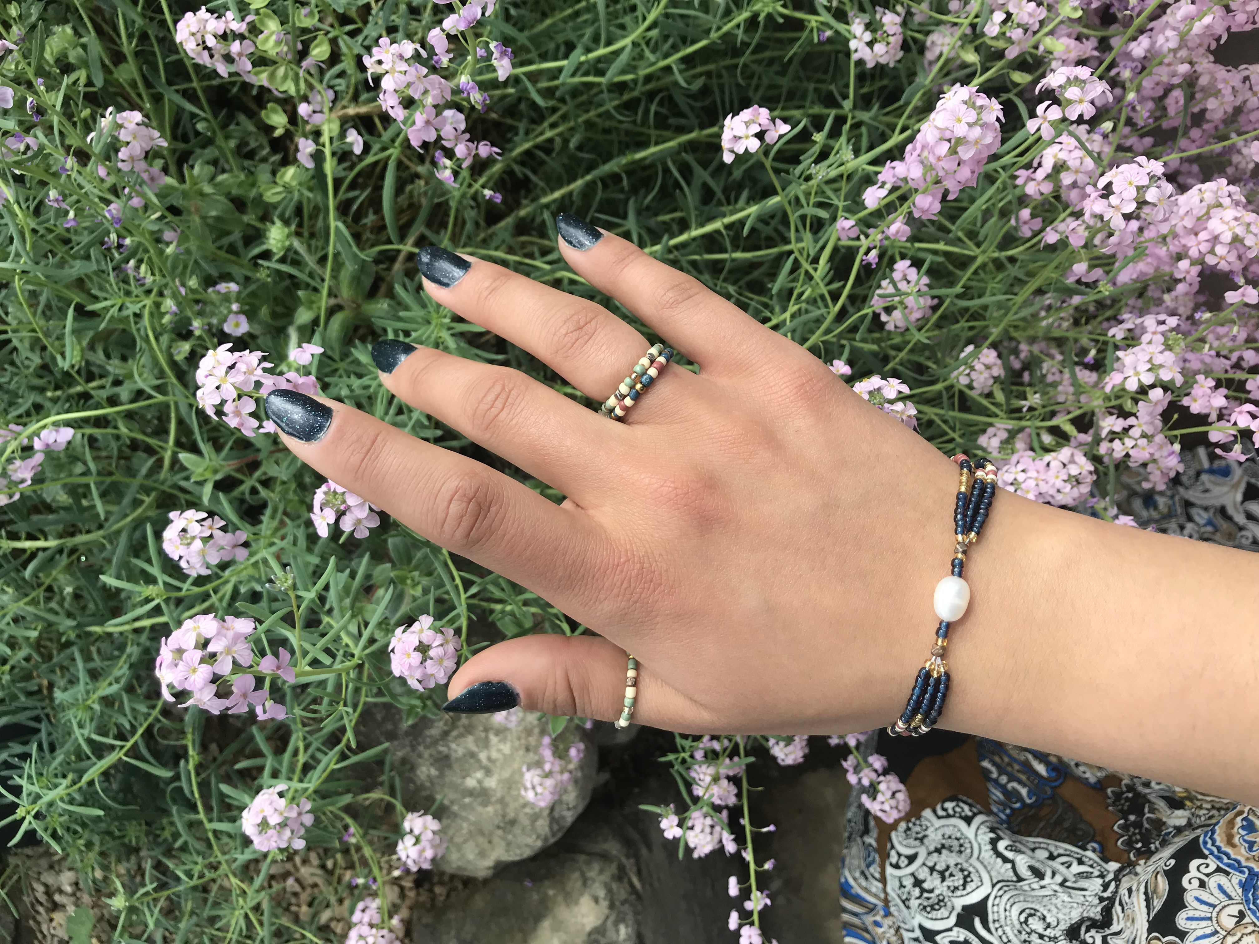 up-cycled, indigo,
            beaded, pearl bracelet and beaded rings on floral background