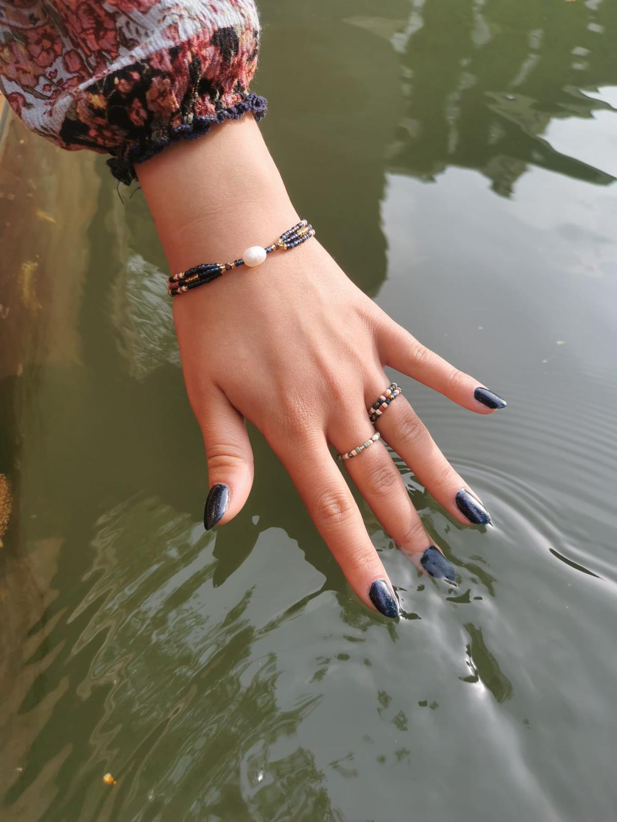 up-cycled, indigo, beaded, pearl bracelet and beaded rings on water background