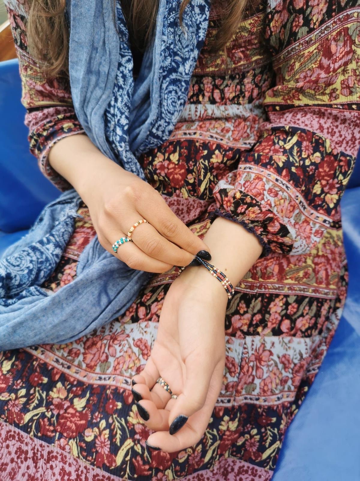 putting on an up-cycled, indigo, beaded, pearl bracelet and beaded rings on a boat